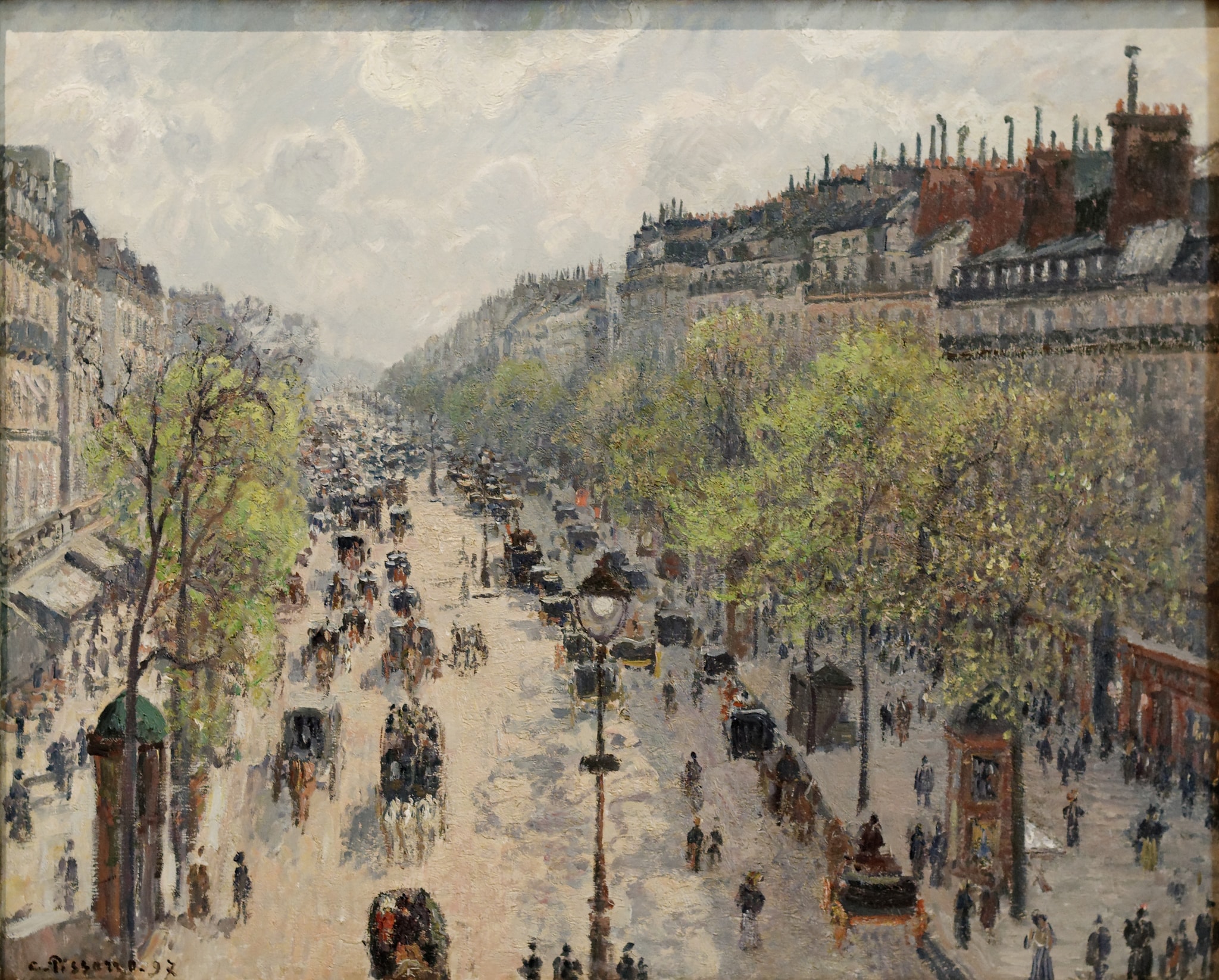 The Boulevard Montmartre on a Spring Morning by Camille Pissarro (1897) featuring Iron streetlamp, Pale boulevard roadway, Early spring trees, Crowds and horse-drawn traffic